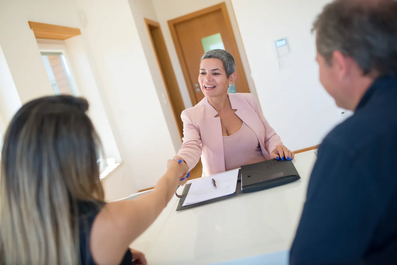A lawyer shaking hands with a client across her desk